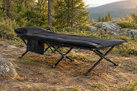 Lit de camp pliable avec coussin amovible et poche latérale installé dans une clairière