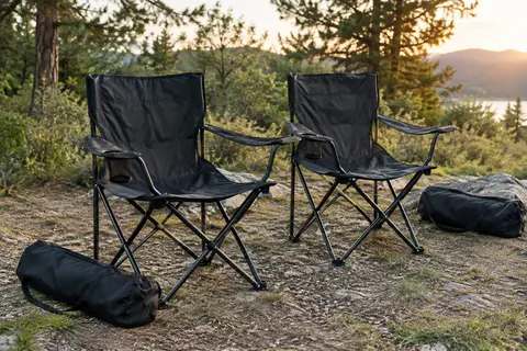 Deux chaises de camping pliantes noires avec porte-gobelet et sacs de transport dans une clairière