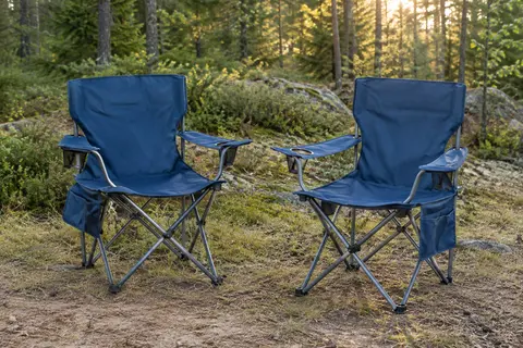 Deux chaises pliantes de camping bleues avec porte-gobelets et poches, installées dans une clairière