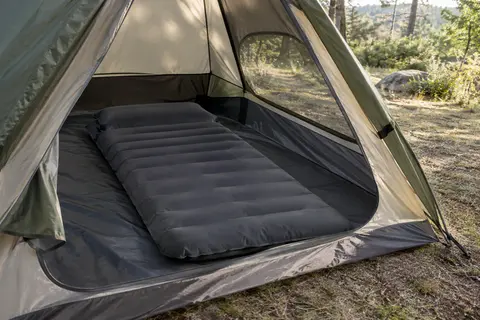 Matelas autogonflant Hikenture gris foncé avec oreiller intégré, déployé dans une tente en clairière