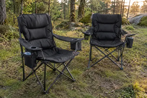 Deux chaises pliantes de camping noires rembourrées, avec porte-gobelet et poche isotherme, dans une clairière