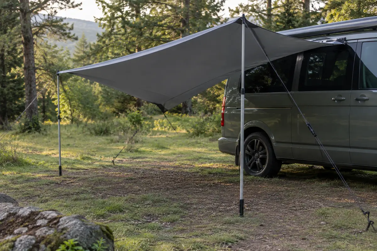 Voile pare-soleil Qeedo gris foncé tendue près d’un van dans une clairière