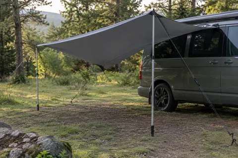 Voile pare-soleil Qeedo gris foncé tendue près d’un van dans une clairière