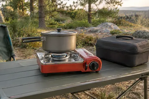 Réchaud de camping rouge à une flamme avec casserole et mallette dans une clairière