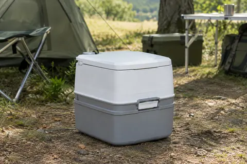 Toilette portable Thetford blanche et grise installée dans un espace de camping sobre